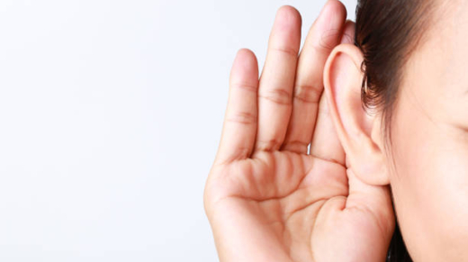 Listening female holds his hand near her ear on white background