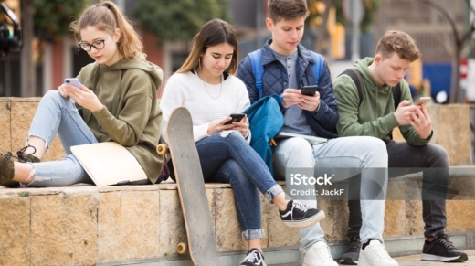 Four teenagers chatting on their smartphone on walking