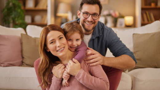 Happy family with little daughter sitting on carpet in living room